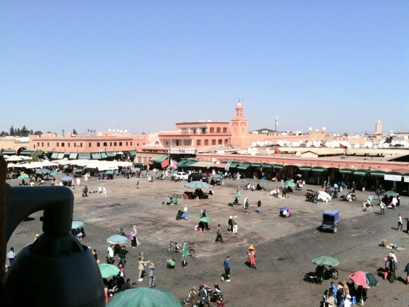 A bustling market square with tents, people, and clear blue skies.