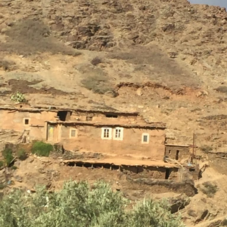 A traditional mud-brick house nestled in a rocky, arid landscape.