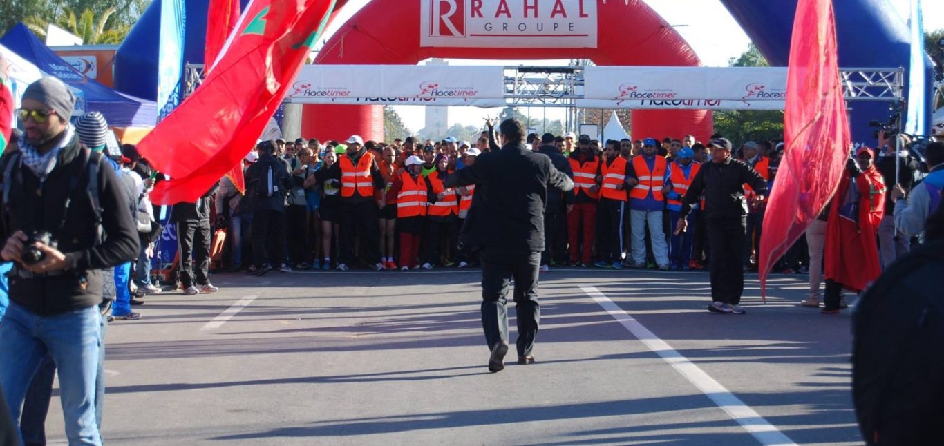 Crowd of participants in bright vests at a sporting event, with flags in the foreground.