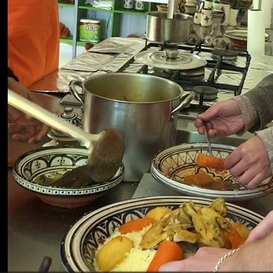 A person serving a stew with vegetables into bowls in a kitchen setting.