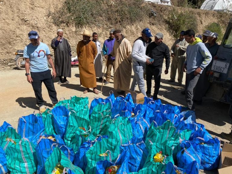 A group of people gathered around bags of supplies on a site.
