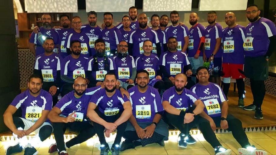 Group of runners in purple shirts posing together at an event.