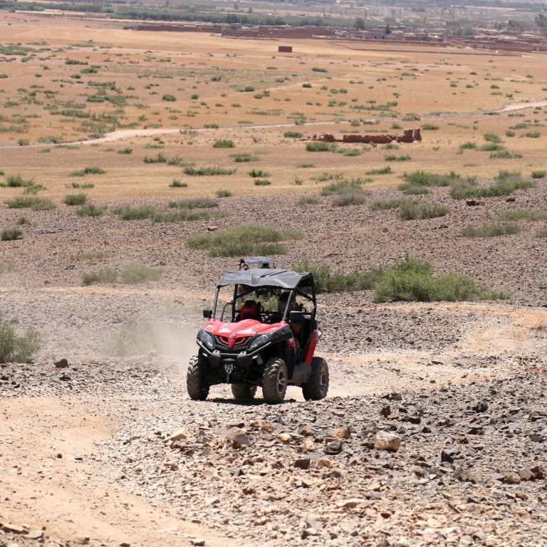 A red and black off-road vehicle driving through a rocky landscape.