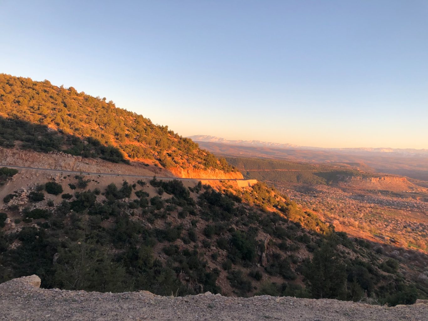Sunset over a rocky landscape with hills and valleys in the distance.