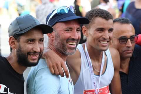 Four men smiling and posing together, celebrating a running event.