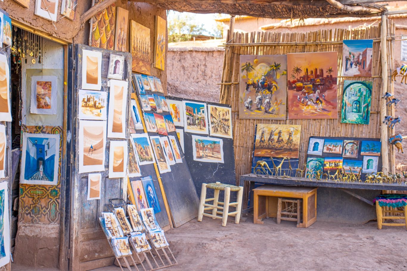 Artisan market showcasing various paintings and artworks displayed on walls and tables.