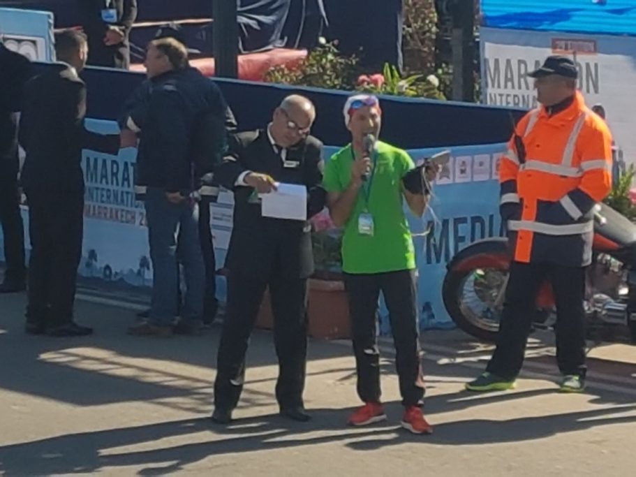 Two men conversing at an event, one in black suit and the other in a green shirt.