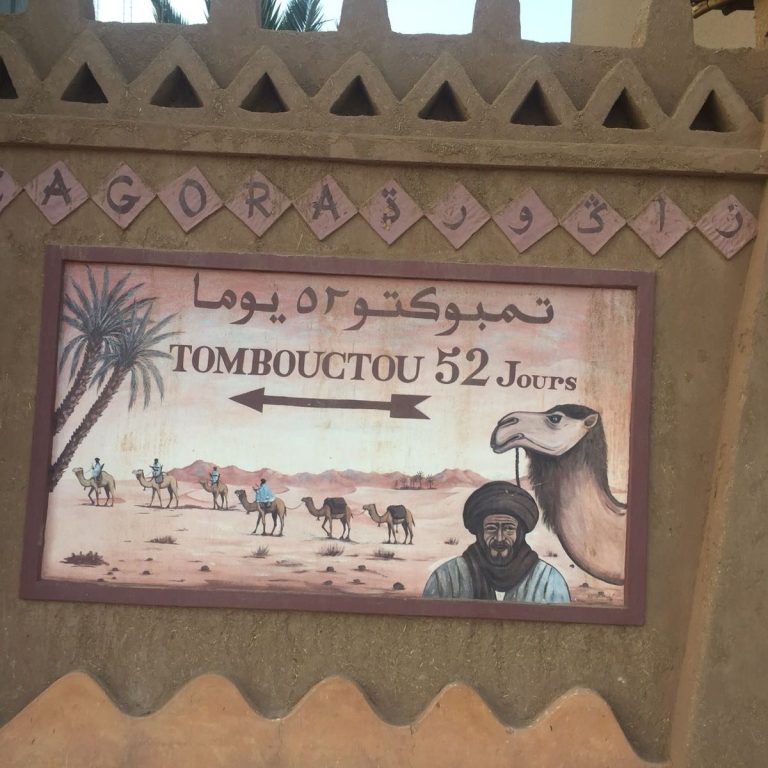 Signpost indicating Tombouctou 52 with a camel and desert scene.
