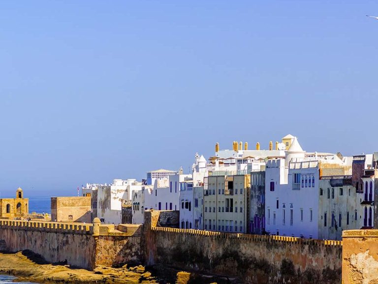 Coastal view of white buildings against a clear blue sky and sea.