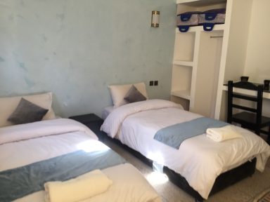 Bright bedroom featuring two twin beds with light bedding and a minimalist decor.