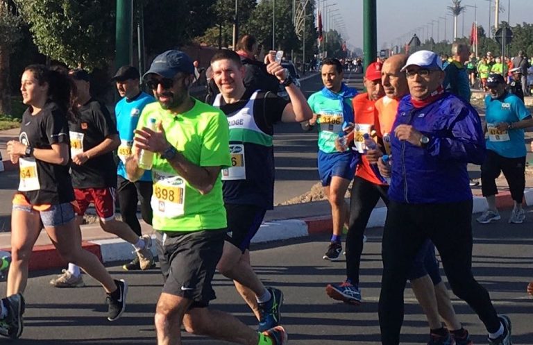 Runners participate in a lively marathon with diverse attire and cheerful expressions.