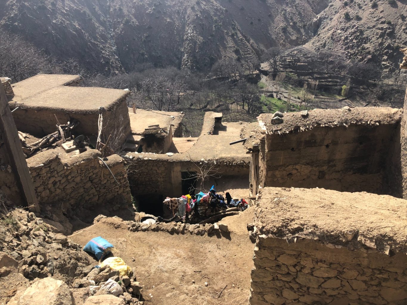 Ruins of stone buildings on a mountainous landscape with scattered debris.