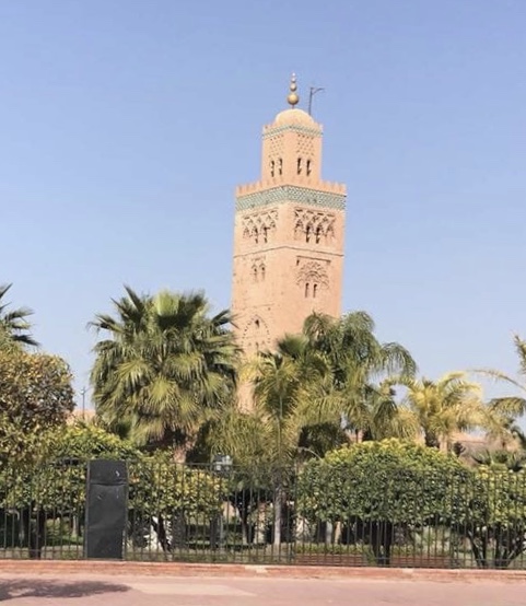 Historic tower surrounded by palm trees and greenery against a clear blue sky.