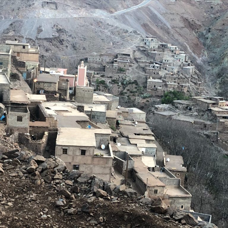 Rugged mountain landscape featuring hillside buildings and barren trees.