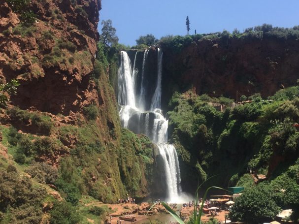 A scenic waterfall cascading down a rocky cliff surrounded by lush greenery.