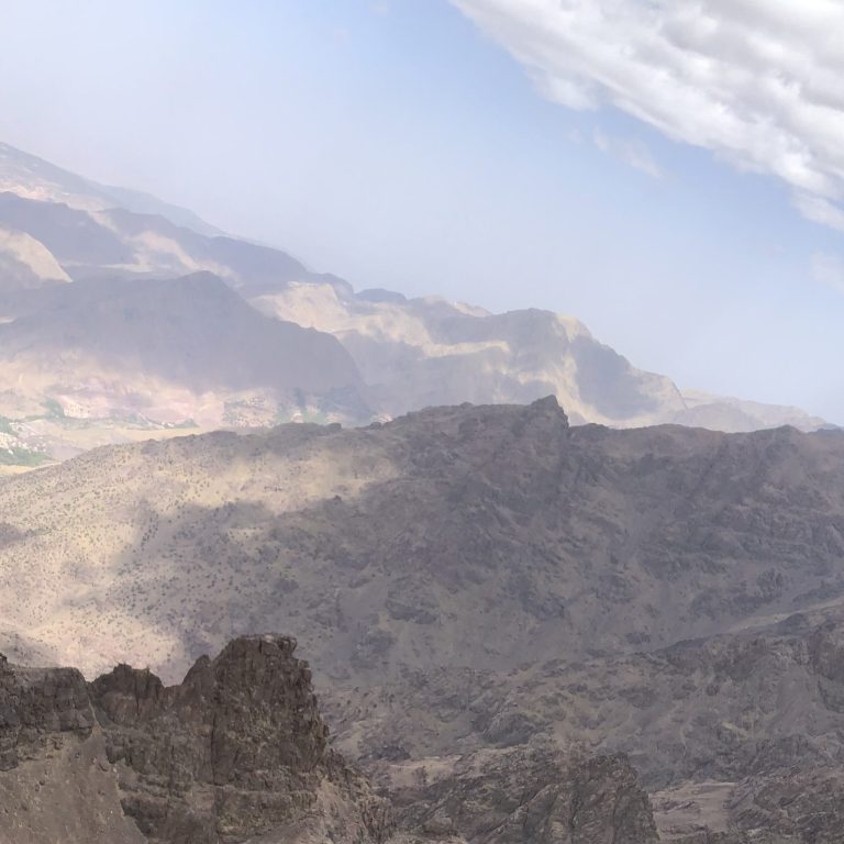 View of rugged mountains under a cloudy sky with valleys below.