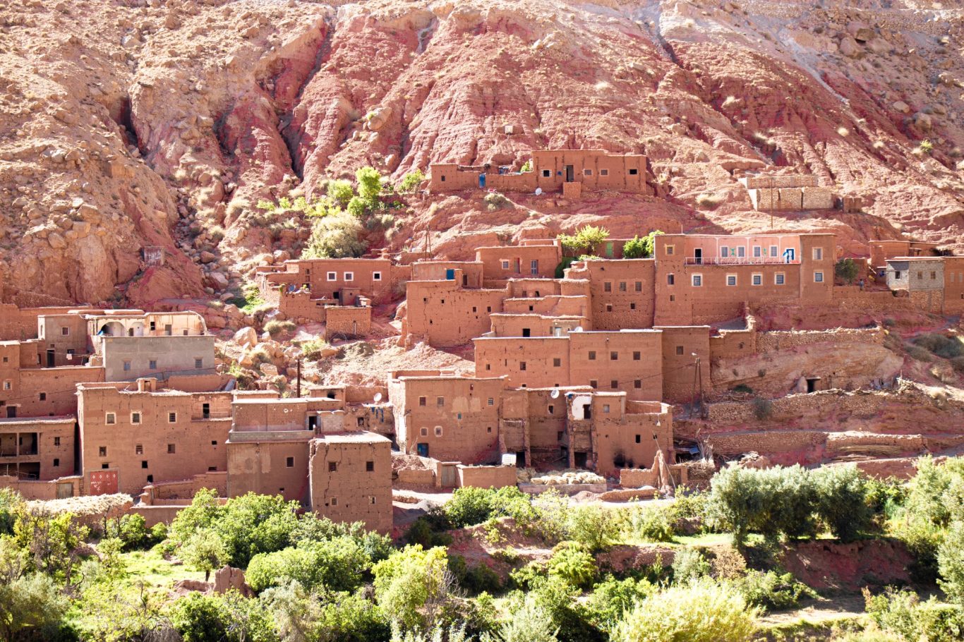 Traditional brick buildings nestled in a rocky landscape with greenery below.