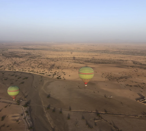 Hot air balloons floating over a vast, arid landscape.