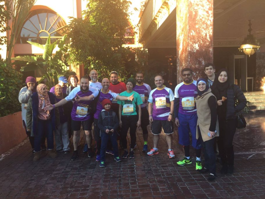 Group photo of runners and supporters, smiling in sports gear outside a building.