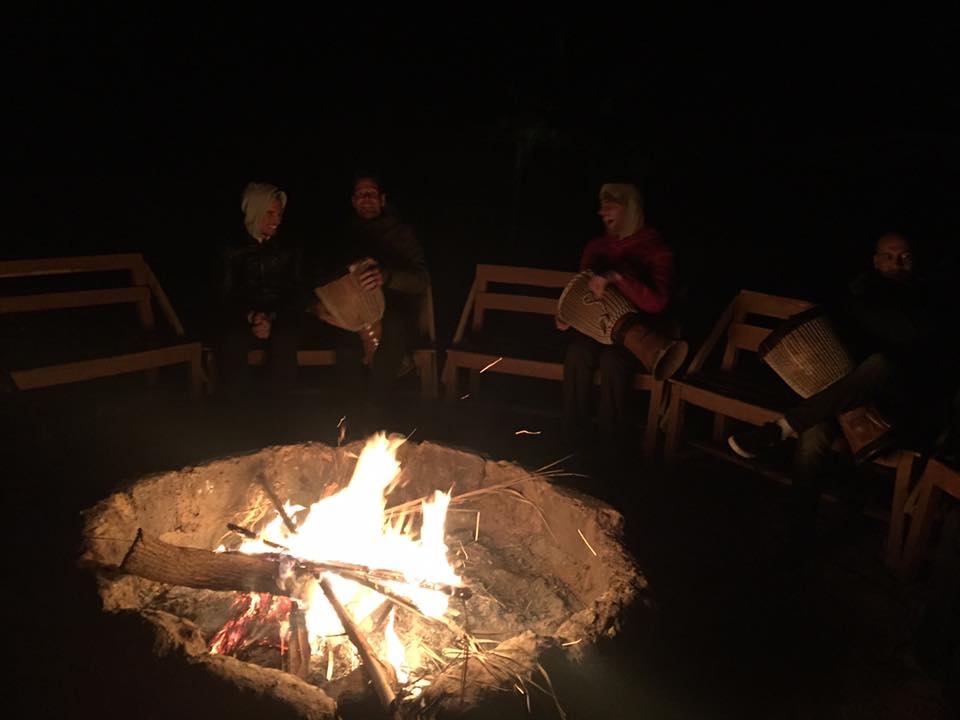 Group of people sitting around a campfire at night.