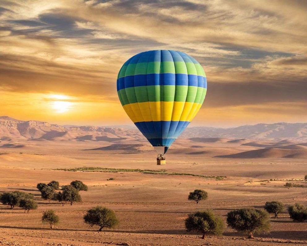 A colourful hot air balloon flying over a desert landscape at sunset.