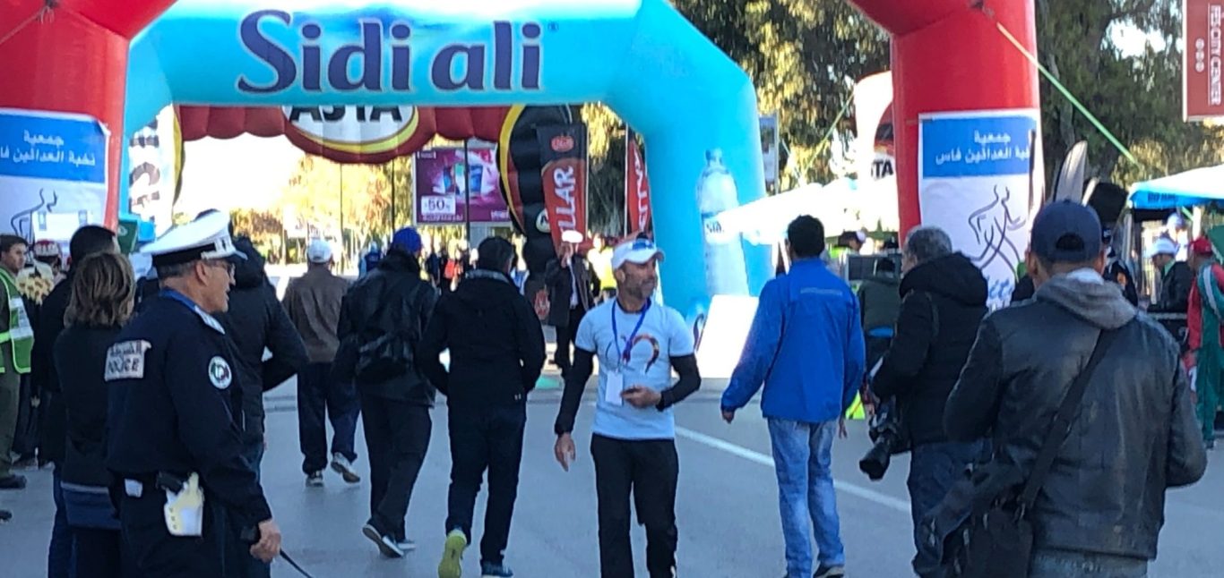 Crowd of participants in bright vests at a sporting event, with flags in the foreground.