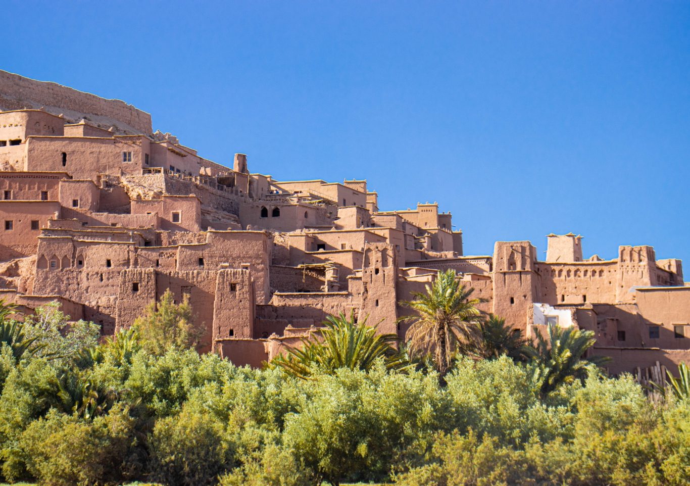 Ancient clay buildings nestled on a hillside, surrounded by lush greenery.